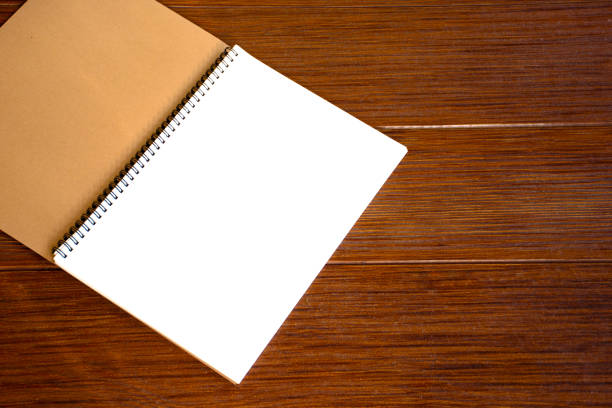 Empty open blank white notebook or blank white paper on a brown wooden plank background with a beautiful pattern.