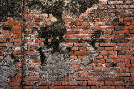 Ancient brick wall surface with water stains, constructed from orange bricks, showcases cracks that symbolize the passage of time.