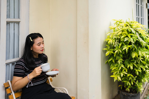 Woman in terrace with cup of coffee