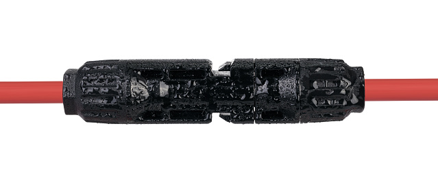 A waterproof electrical connector fastened to a red cable, ready for secure outdoor electrical installations.