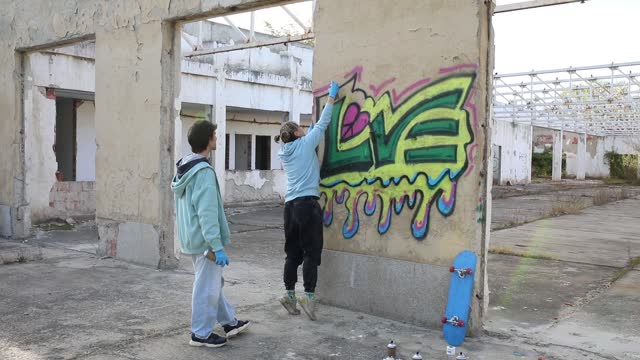Two young people enjoy the day drawing colorful graffiti, concept of love