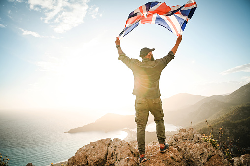 Man with the English flag on the background of the sea and mountains