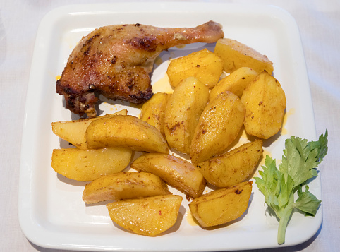 A plate of fast food featuring a crispy duck leg and golden home fries, all freshly fried and ready to be devoured