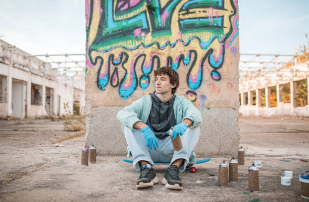 istock A artist sits contentedly in front of the wall on which he has drawn graffiti 2038096013