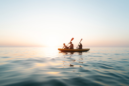 Photo of a family paddling on the ocean, enjoying their summer holiday away from the city hustle.