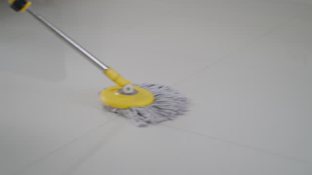 Closeup mop sweeping the floor cleaning service. Households washes tiled floor,