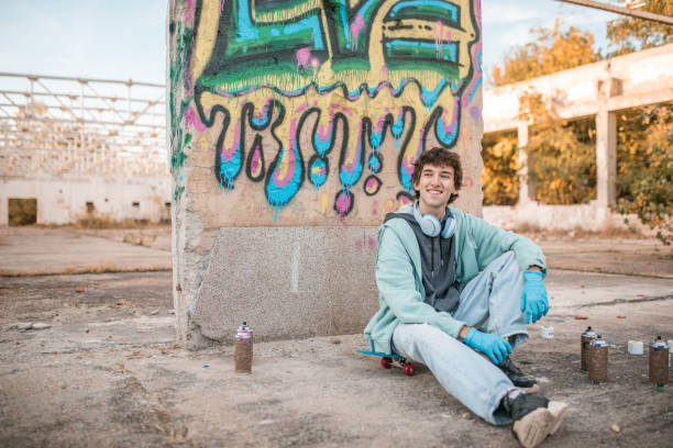 istock A smiling artist sits contentedly in front of the wall on which he has drawn graffiti 2038103143