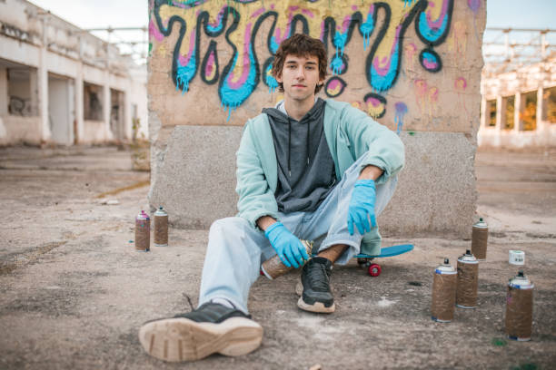 istock A young male artist looks directly into the camera while sitting in front of a graffiti he has drawn 2038106936