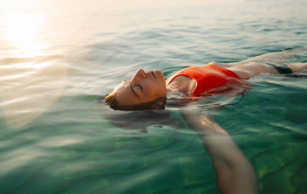 Mid adult woman swimming in the calm sea water Photo of a mid adult woman swimming in the calm ocean. floating woman stock pictures, royalty-free photos & images