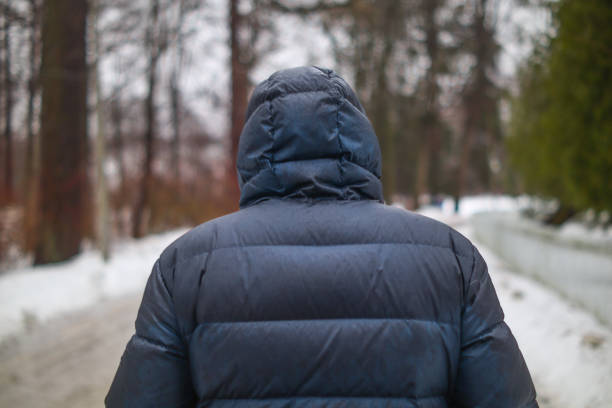 Rear view of a man in a jacket walking through a winter park