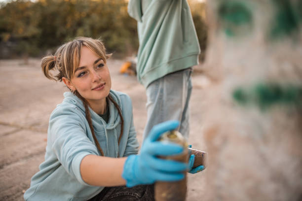 istock Lovely woman holding spray paint in hands while drawing graffiti with friend 2038131213