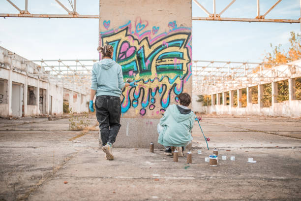 istock Rear view of two friends drawing graffiti and creating their art 2038140369
