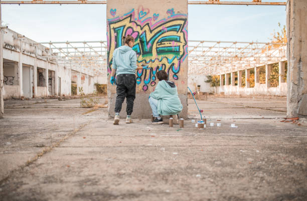 istock Rear view of two talented friends drawing graffiti and creating their art 2038140923
