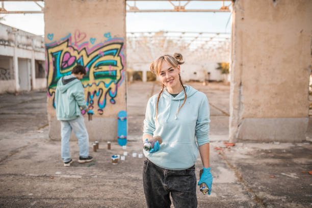 istock Smiling female artist looking directly into the camera while her friend draws graffiti 2038143054