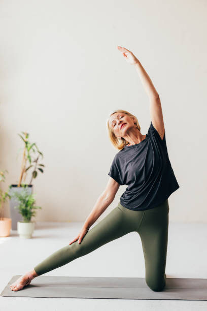 istock Senior Woman Practicing Yoga Pose in a Bright Room with Plants 2038148991