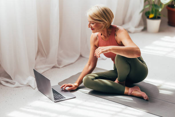 istock Active Senior Woman Using Laptop During Home Fitness Session 2038149021