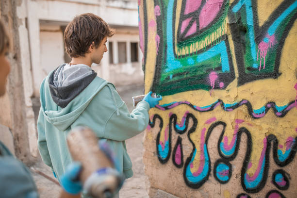 Paris, France - October 27, 2025: Young men posing and taking photos on Rue Denoyez, an alley in the Belleville district filled with murals.