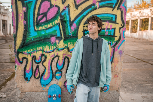 Young girl in a white tracksuit dancing against the background of a wall with yellow graffiti