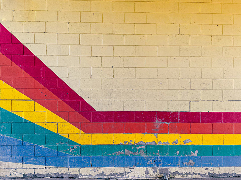 A rainbow painted on a yellow brick wall