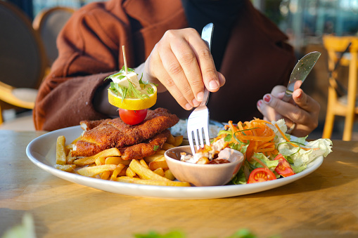 women eating Chicken schnitzel served with potato chips .