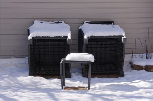 Garden furniture in snow in the residential home backyard patio on winter day.