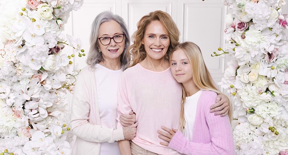 Three generations of women. Mother, grandmother and granddaughter look at camera during a family photo shoot