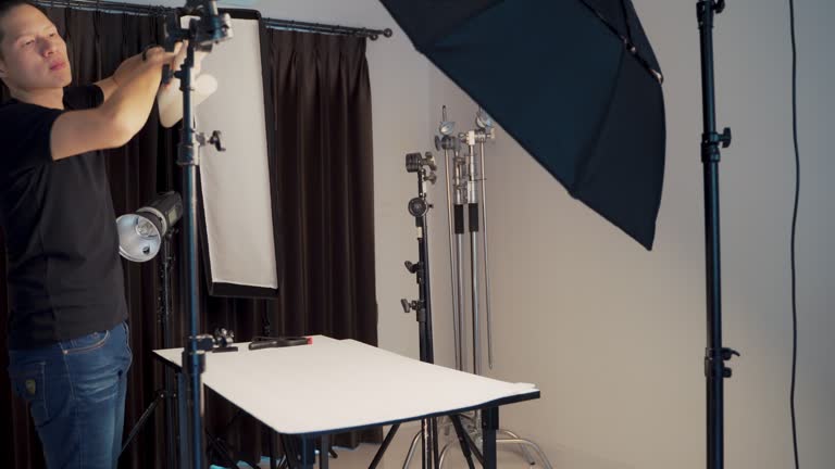 Asian assistant photographer setting limbo white background in studio