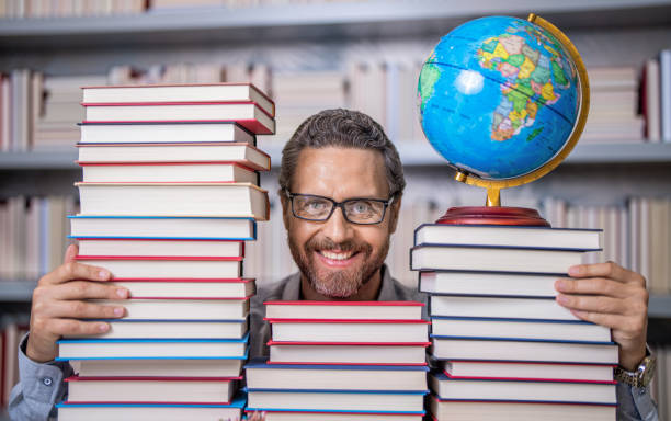 istock Teachers Day. Tutor at classroom. Man geographer with books in classroom. Knowledge and education concept. school teacher with book in classroom. teacher in classroom. Lost in a good book 2038229578