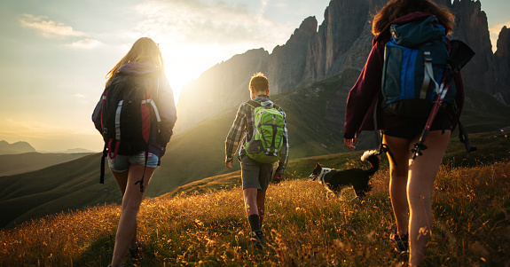 Adventures on the Dolomites: teenagers hiking together with a border collie dog in Val Gardena and Val di Fassa
