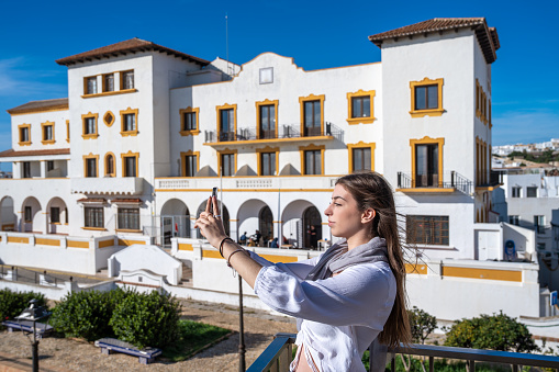 Brunette young woman tourist selfie photo in Tarifa skyline of Cadiz surf city of Andalusia Spain