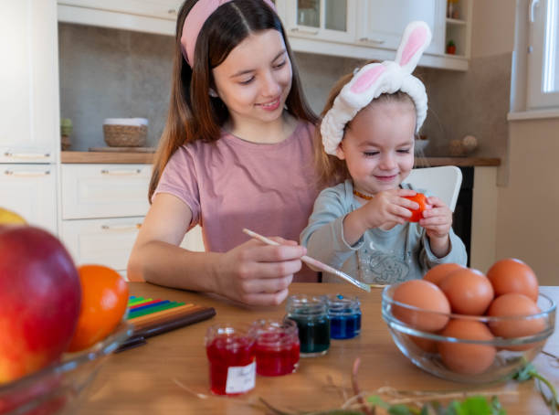 istock Older and younger sister are playing and coloring Easter eggs and laughing 2038282586