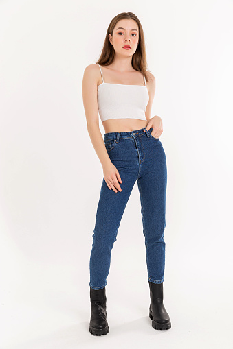 Brunette young woman wearing white tank top and blue jeans. sleeveless, comfortable jeans and black boot.