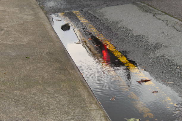 двойные желтые линии в луже воды на дороге - double lane стоковые фото и изображения