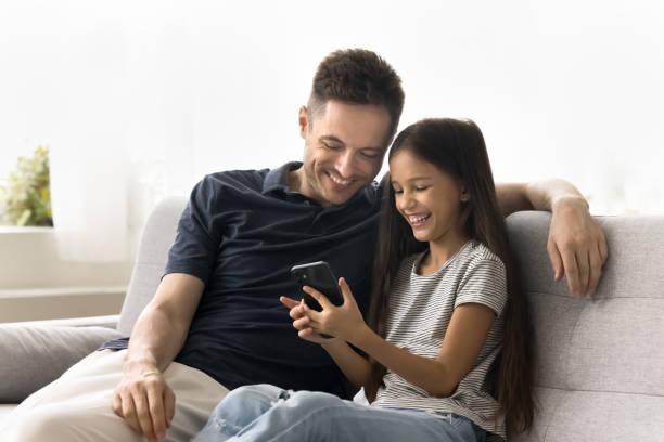 istock Cheerful daughter kid showing funny online content to happy daddy 2038322424