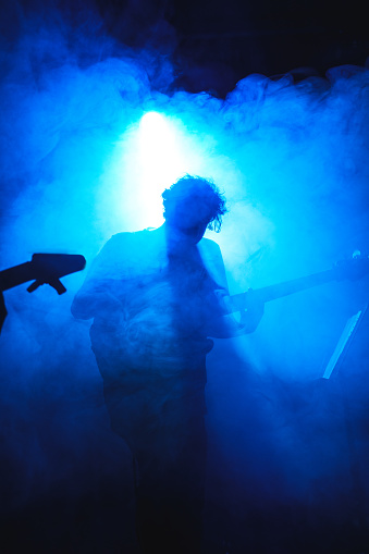 A black male guitarist is singing and playing the acoustic guitar on stage.