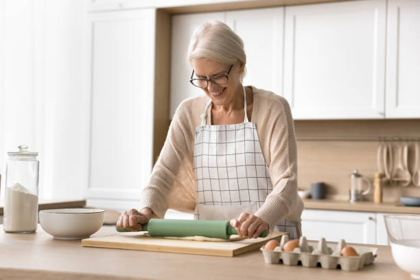 istock Positive mature baker woman wearing apron, rolling dough 2038328315