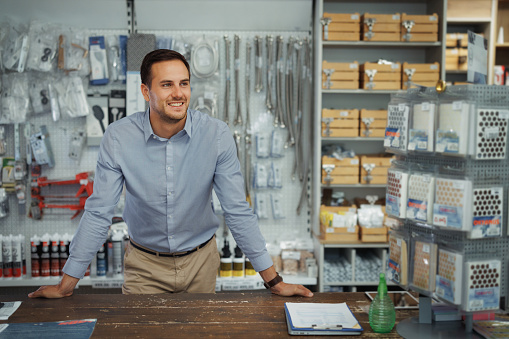 Portrait of handsome well dressed young man standing at counter at hardware store
