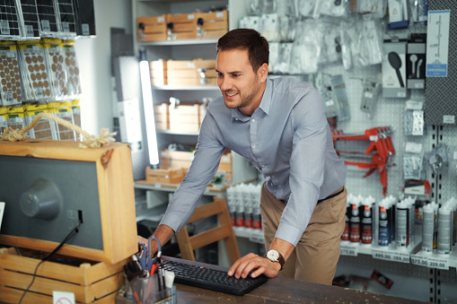 Young handsome man using computer at hardware store