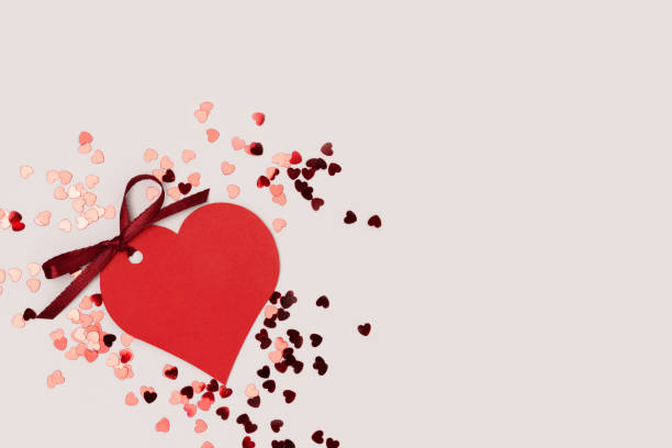 istock Red empty tag in a heart shape with tied ribbon bow and confetti. 2038336895