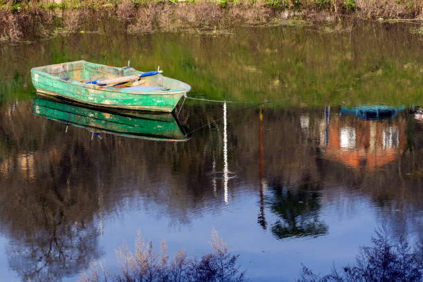 Wooden green old boat on the lake, reflection of the boat on the water. Authentic wooden boat.