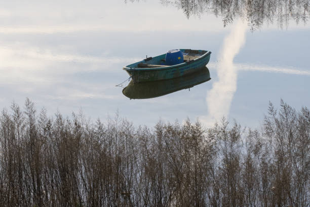 Wooden green old boat on the lake, reflection of the boat on the water. Authentic wooden boat.