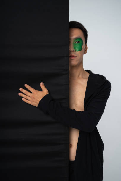 Half Face of Man with Green Face Paint Peeking from Behind Black Panel