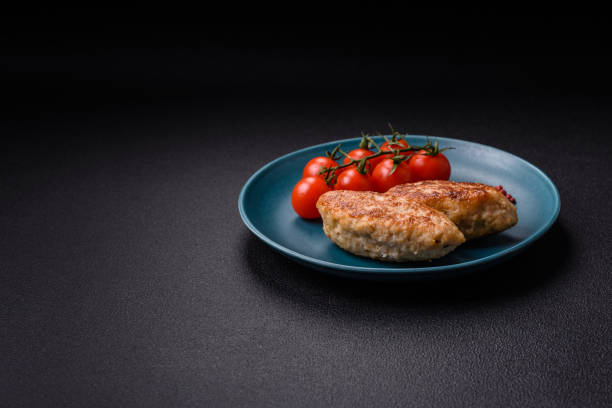 Delicious fresh fried minced fish cutlets with spices and herbs on a dark concrete background