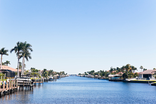 Beautiful canal with waterfront homes and villas with jetties and boats in southwest Florida, USA.