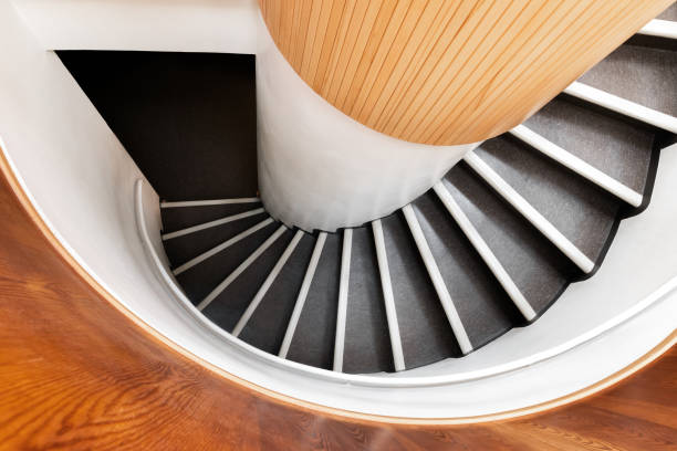 istock Black spiral staircase goes down in wooden interior, top view 2038403419