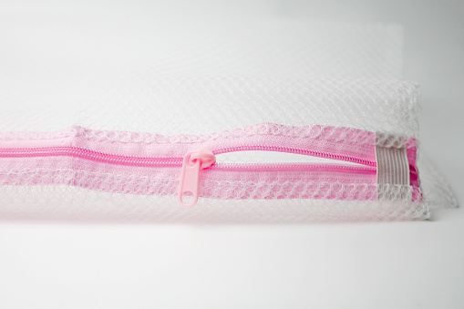 Close up half open pink zipper on mesh fabric isolated on white background