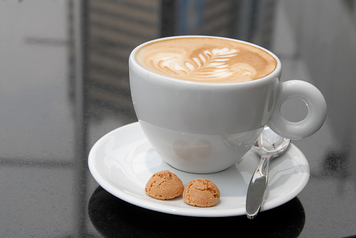 cup of cappuccino coffee with cookies on dark marble table, drink