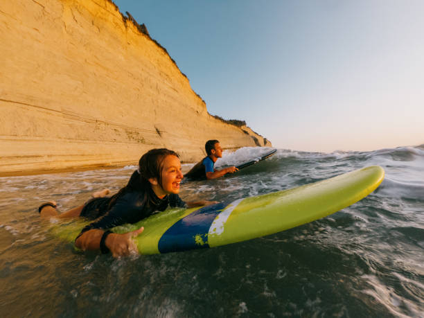 teenagers having an  active life surfing on the beach in the summer - surfing teenage girls friendship sunset - fotografias e filmes do acervo