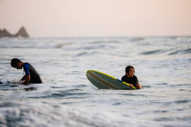 teenagers having an  active life surfing on the beach in the summer - surfing teenage girls friendship sunset photos et images de collection