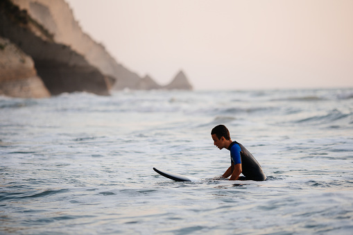 Teenage boy having an active life surfing on a waves on the beach